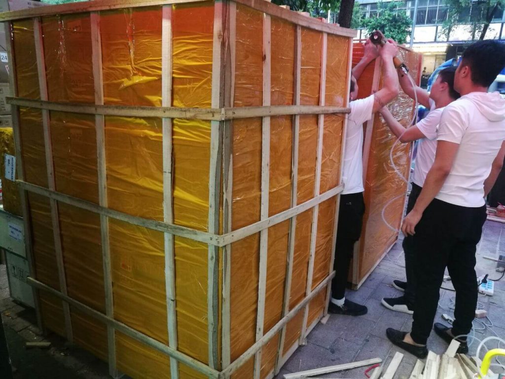Рабочие собирают деревянную обрешётку вокруг груза перед отправкой